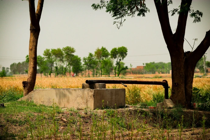 Water pump in a rural field with trees